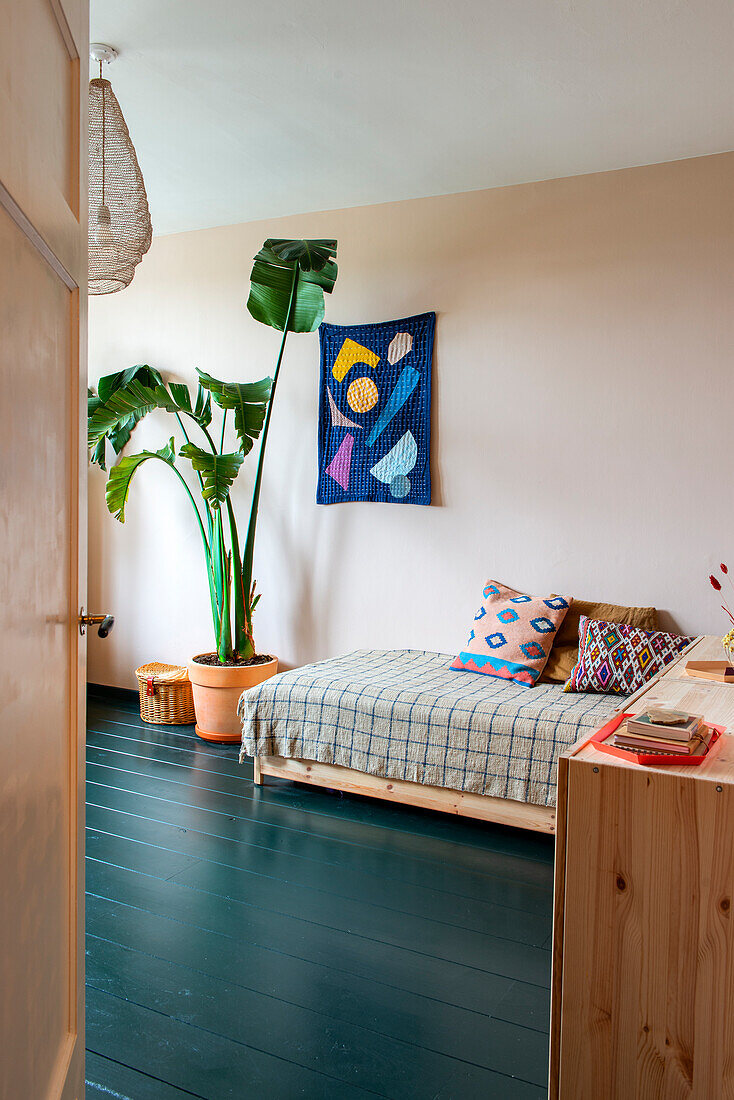 Bright bedroom with day bed, teal wooden floorboards and houseplant