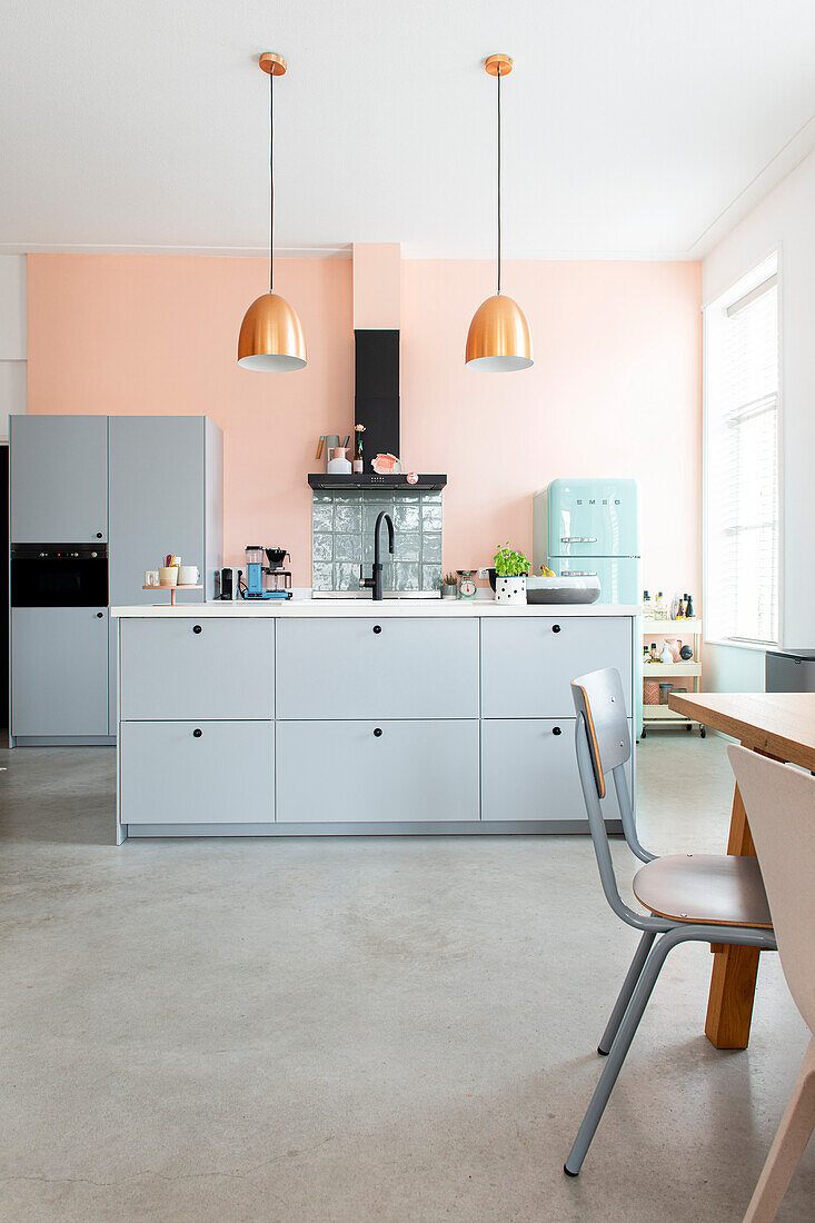 Moderne Küchenzeile mit Leuchten aus Kupfer und pastellfarbenen Wänden