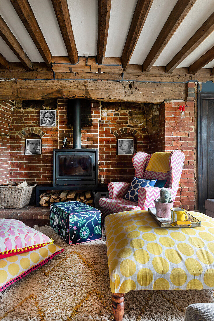 Living room with fireplace, bricks, colourful patterned textiles and exposed beams