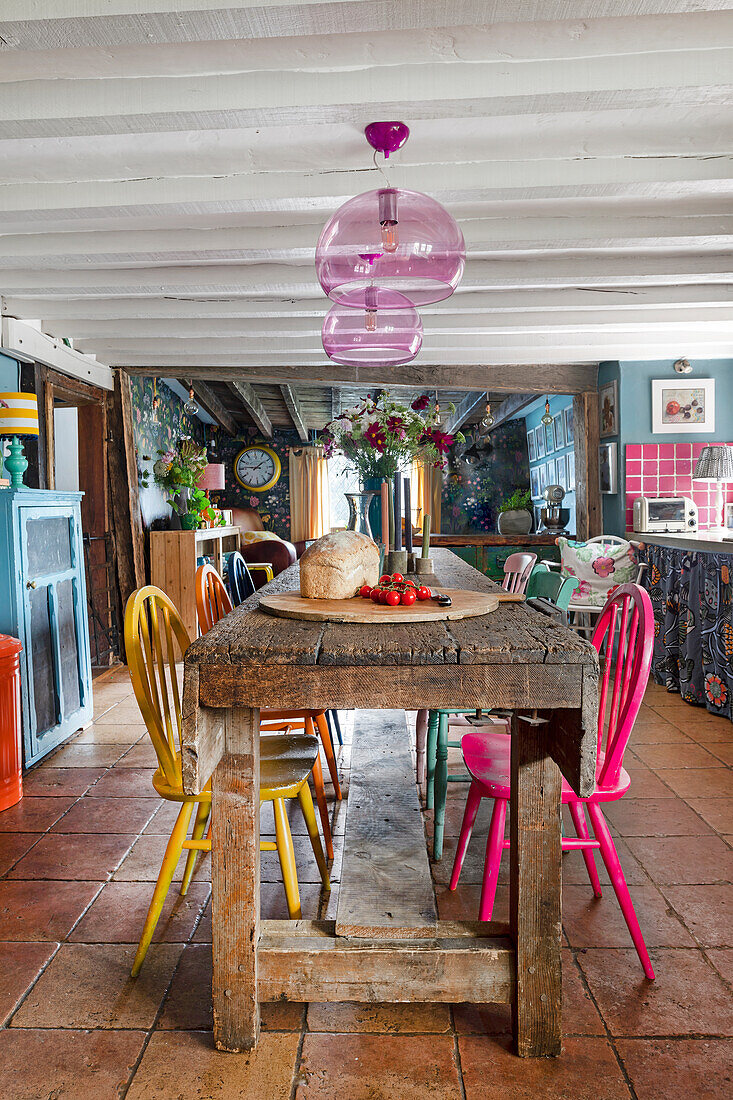 Rustic dining table with colorful chairs in country kitchen
