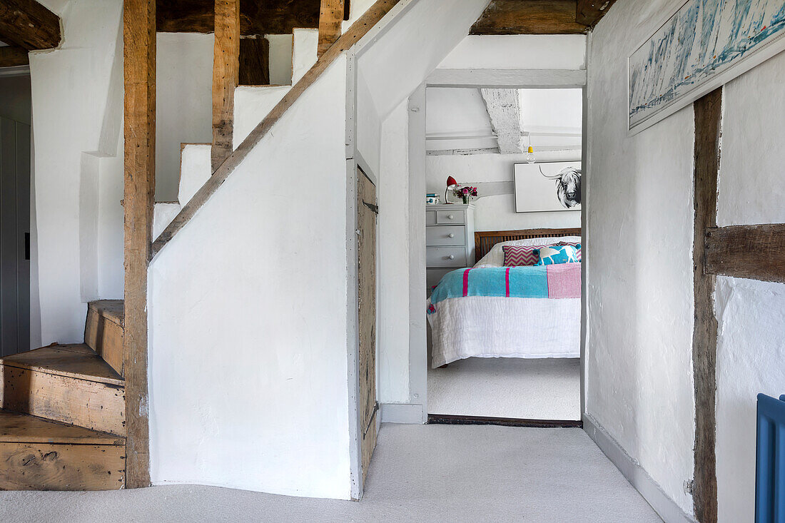 Country-style bedroom with exposed beams and wooden staircase