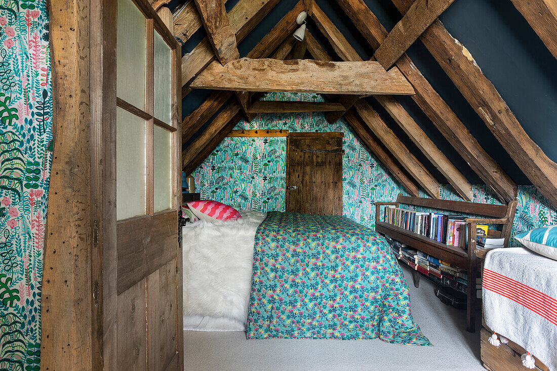 Attic bedroom with exposed beams and floral pattern wallpaper