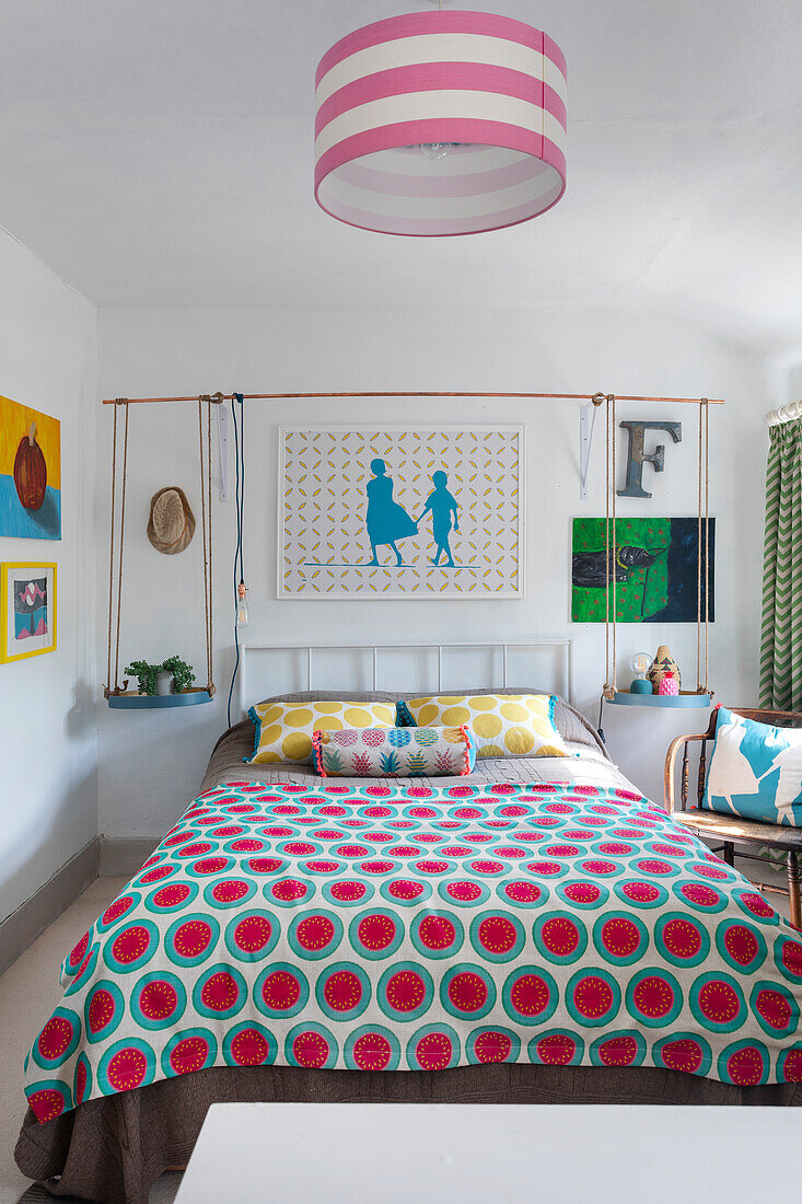 Buntes Schlafzimmer mit gemustertem Bettbezug und moderner Kunst