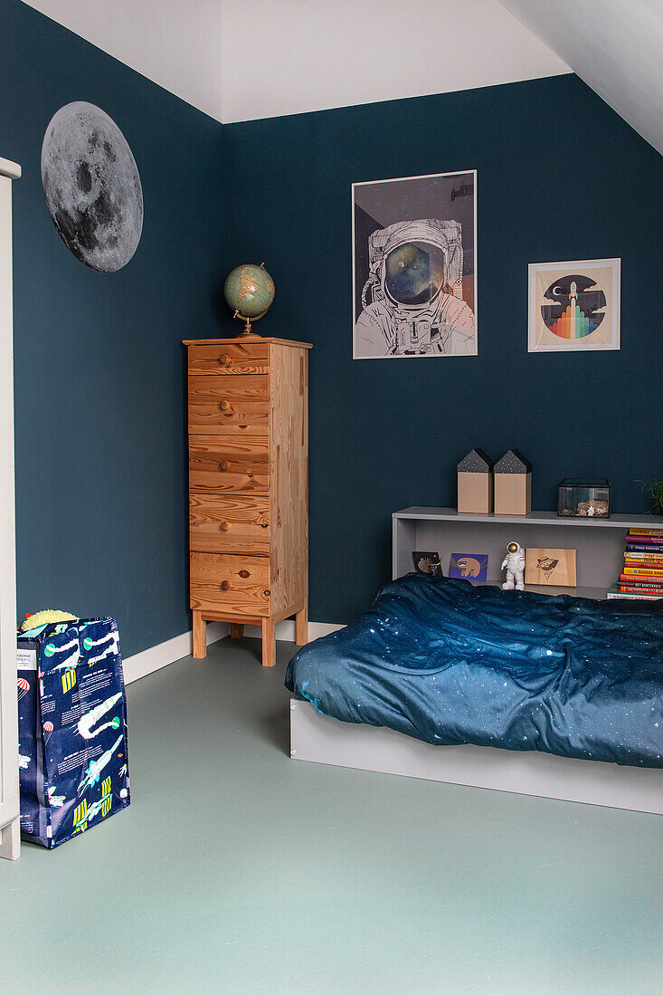 Children's room with space theme and narrow wooden chest of drawers