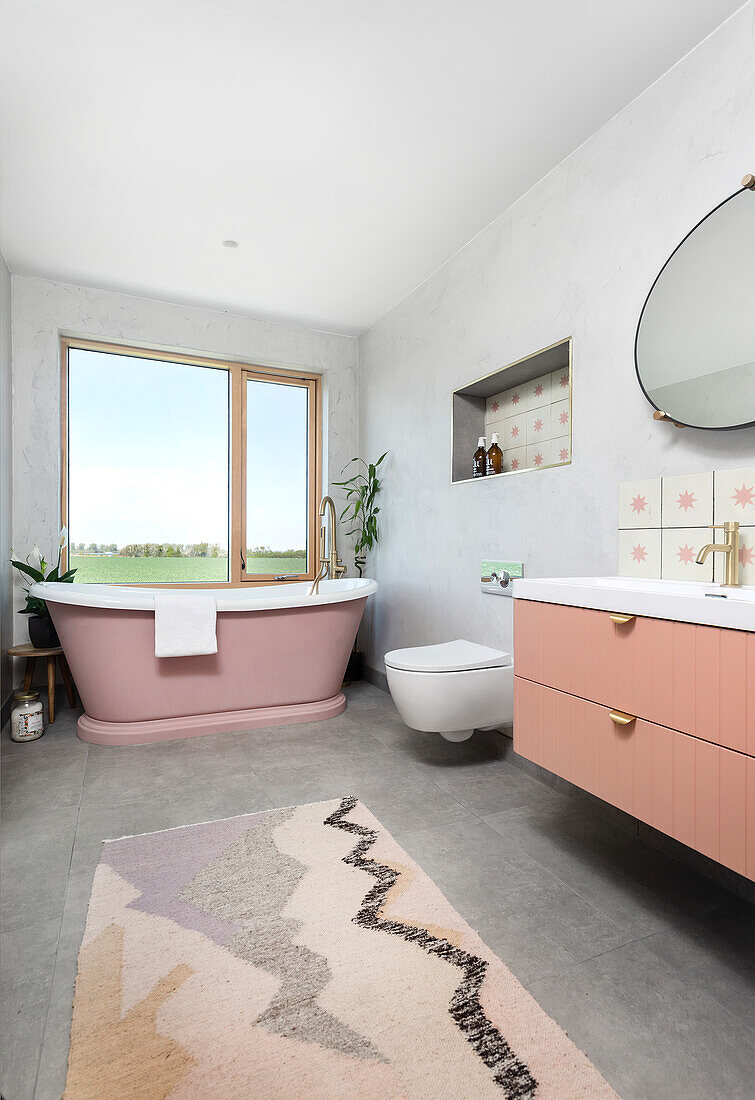 Modern bathroom with free-standing pink bathtub and patterned carpet