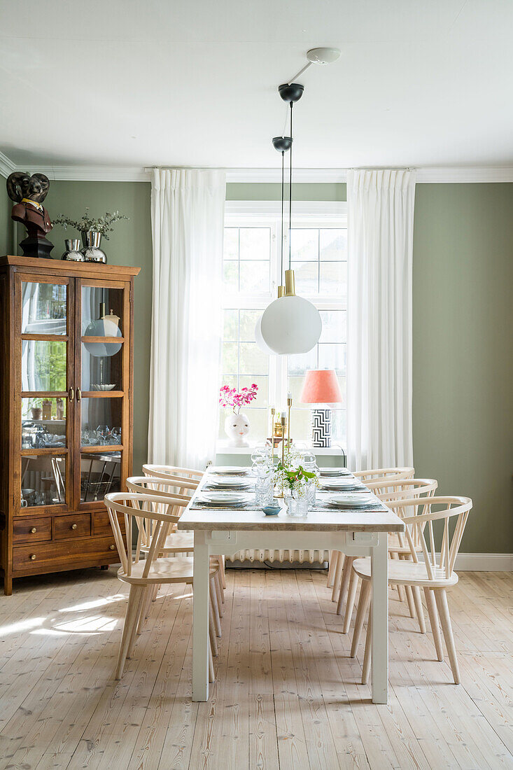 Dining room with light-colored wooden furniture and green-painted walls