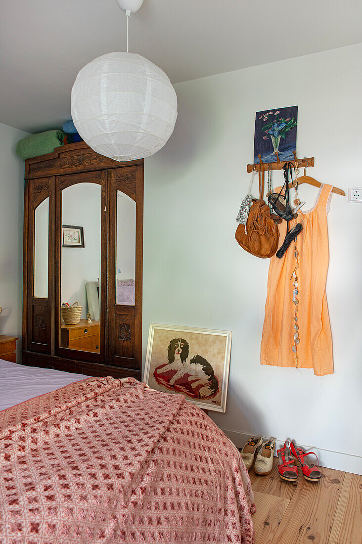 Bedroom with antique wardrobe and dress on wall hooks