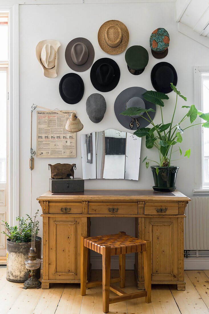 Wooden desk with mirror and hats as wall decoration