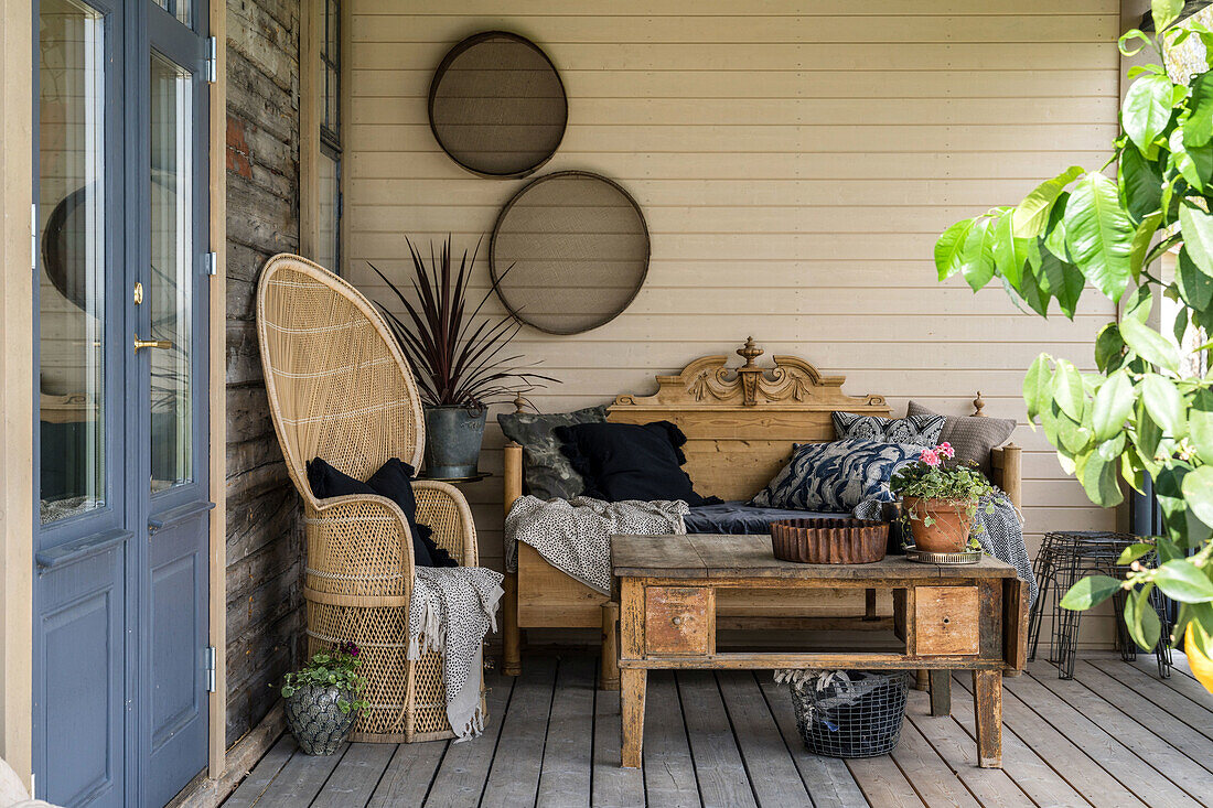 Überdachte Terrasse mit Holzboden, Vintage-Holzmöbeln und Pflanzen