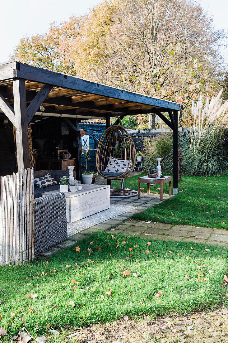 Covered seating area with hanging chair in the autumn garden