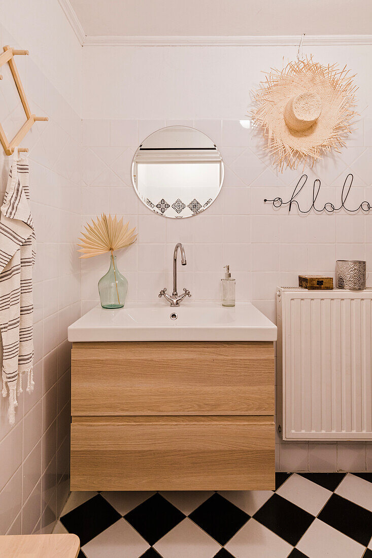 Bathroom with wooden furniture and black and white tiled floor