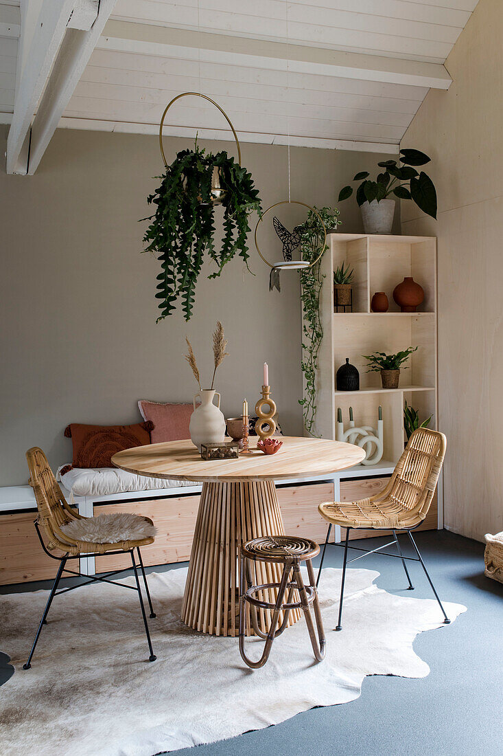 Dining area with round wooden table, rattan chairs and indoor plants