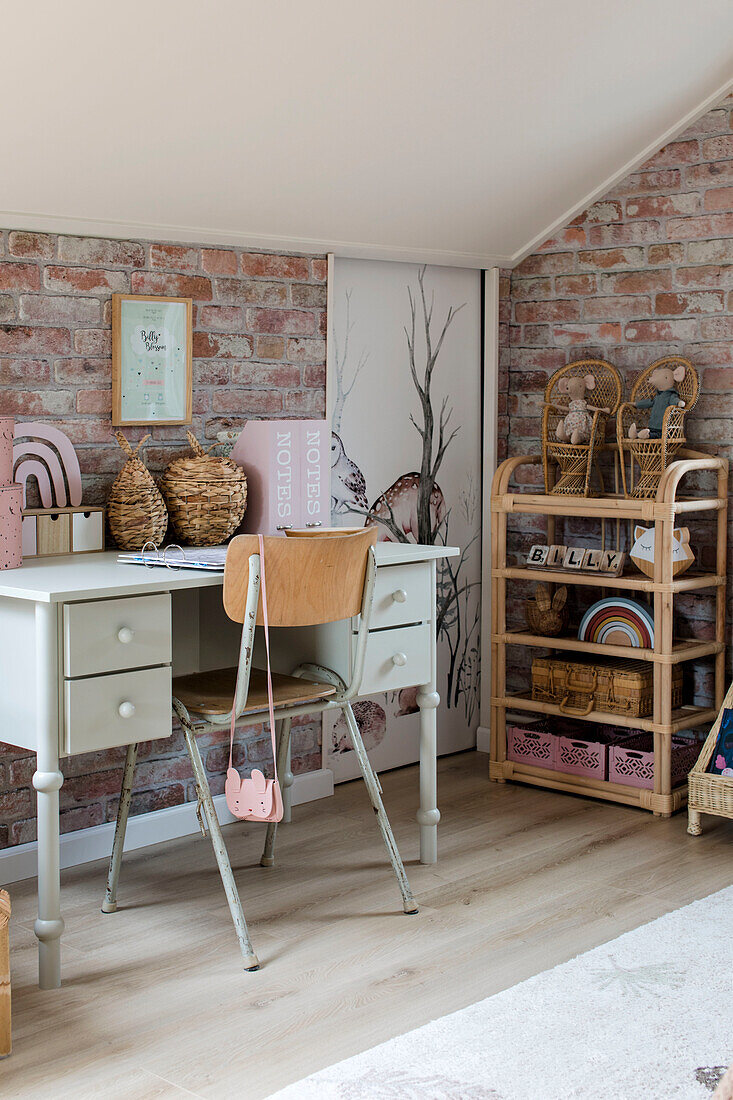 Work corner of a teenager's room with desk and shelf in front of a brick wall