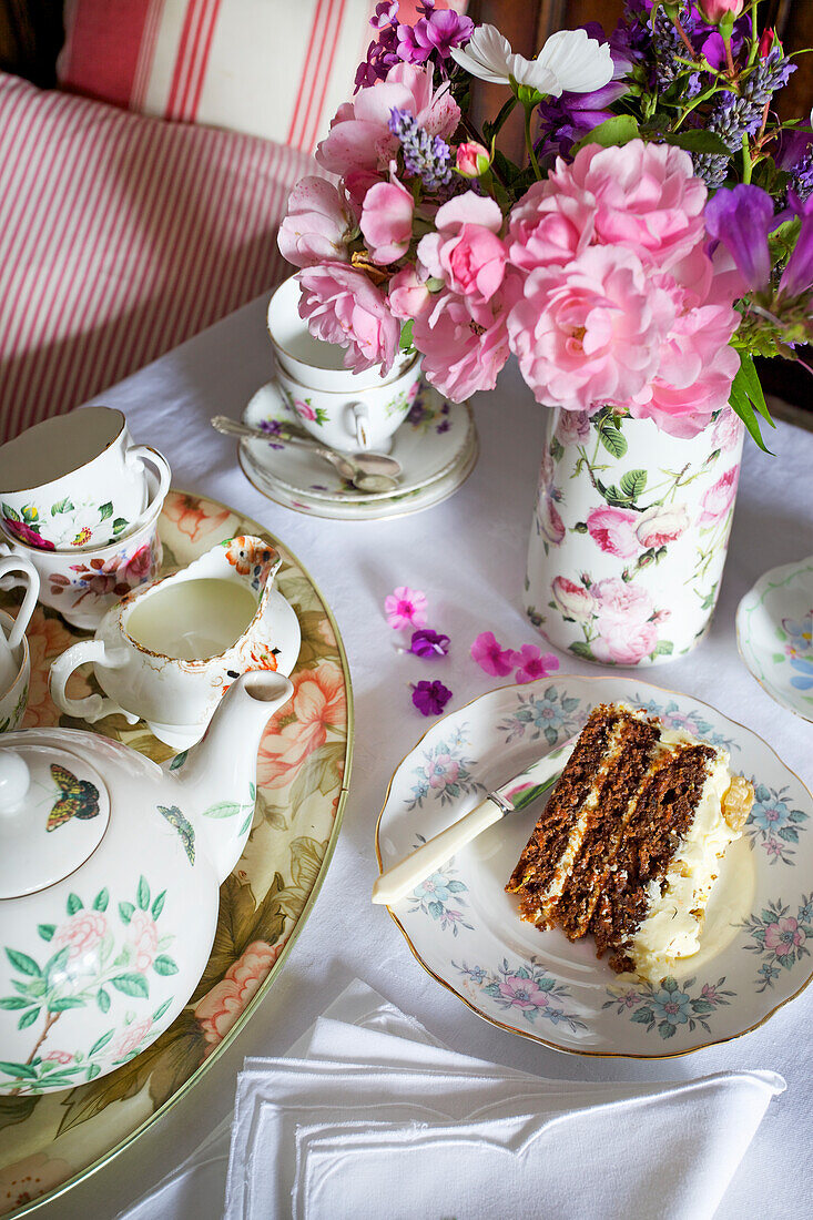 Flowery tea service with a slice of carrot cake and a bouquet of flowers