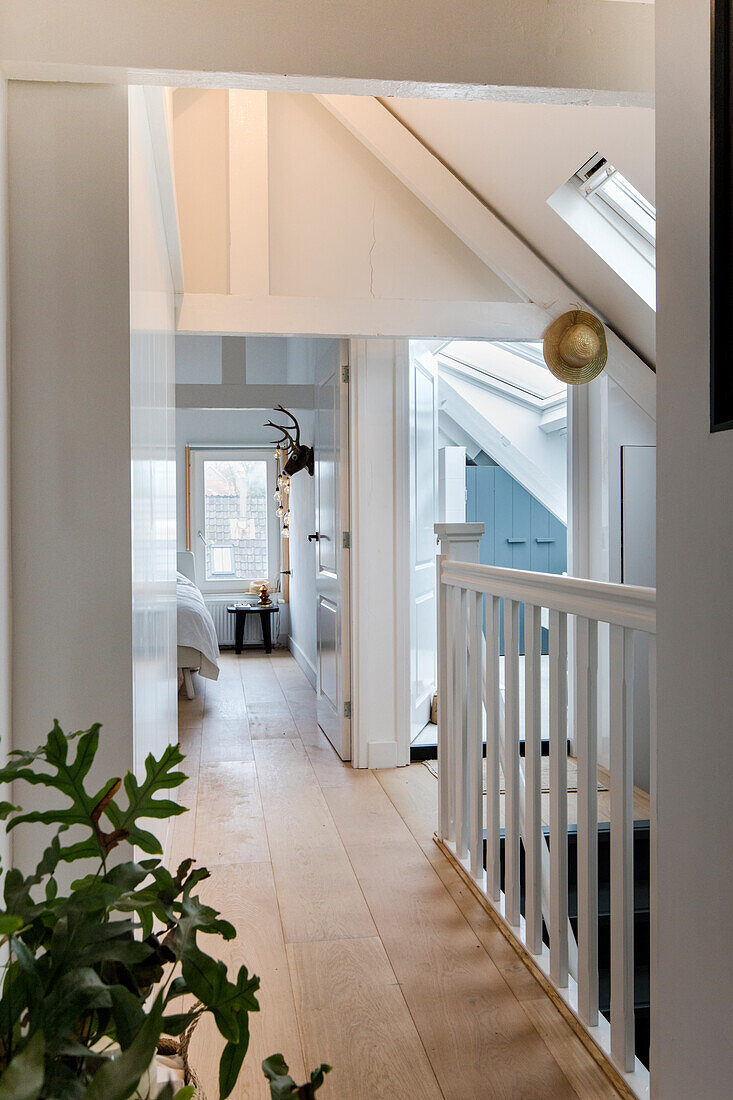 Attic hallway with white beams, skylights and parquet flooring