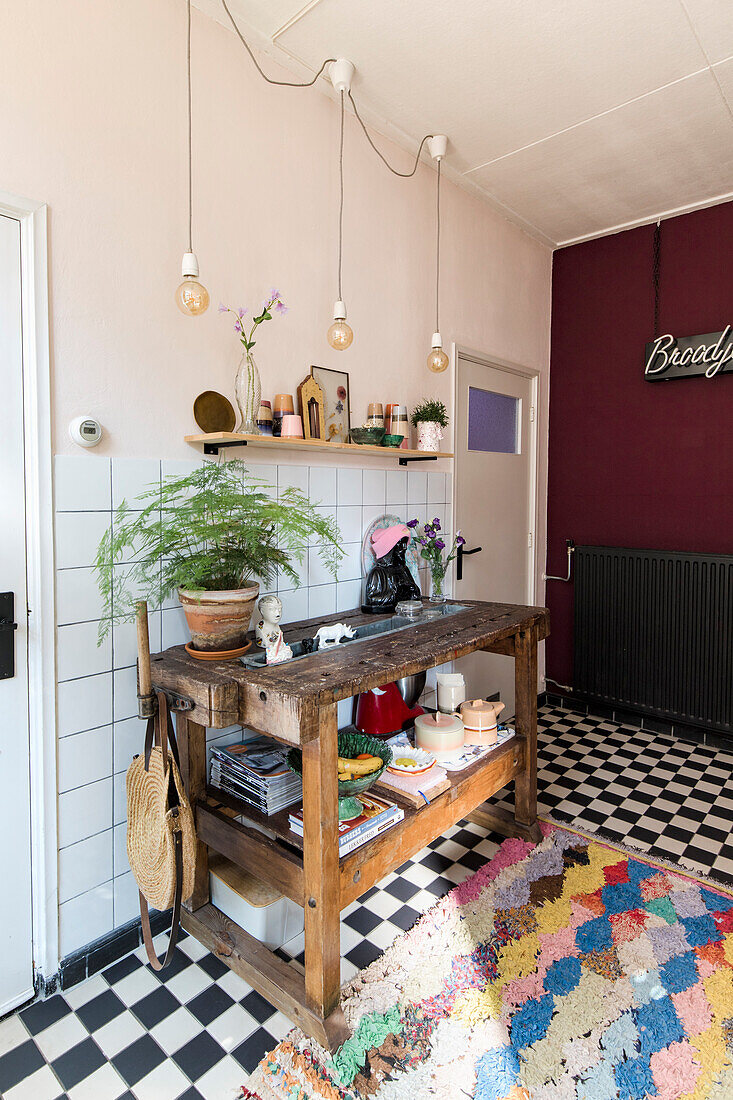 Rustic wooden console with kitchen utensils, chequerboard pattern floor and colourful carpet