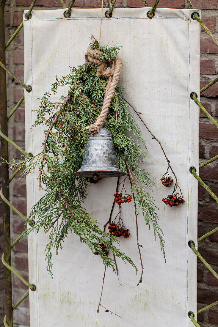 Wall decoration made of metal bell with juniper branches and berries