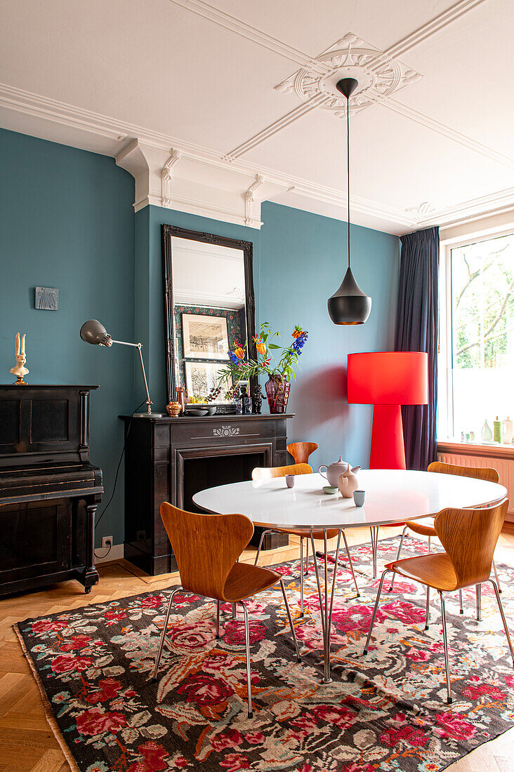 Dining room with blue-green wall, round dining table and patterned carpet