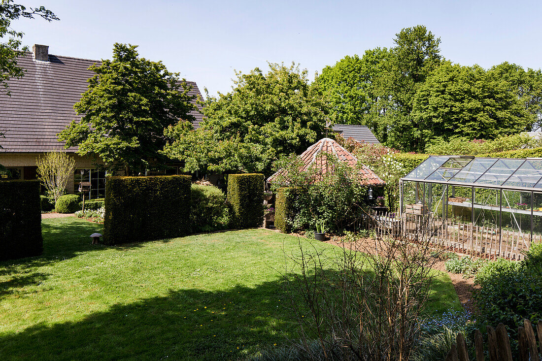 Großer Garten mit Gewächshaus und gepflegtem Rasen im Frühling