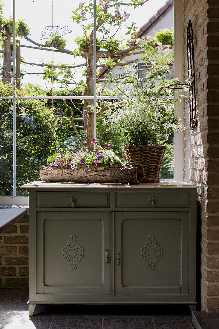 Küchenschrank mit Korb und Blumenkasten vor Gartenfenster