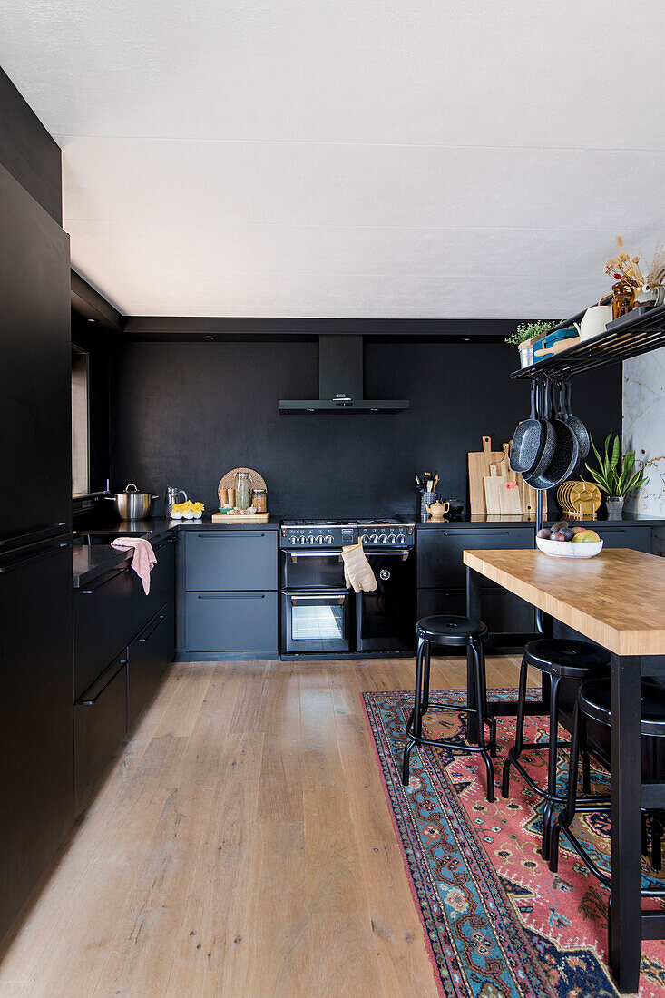 Black fitted kitchen with dark wall and oriental rug