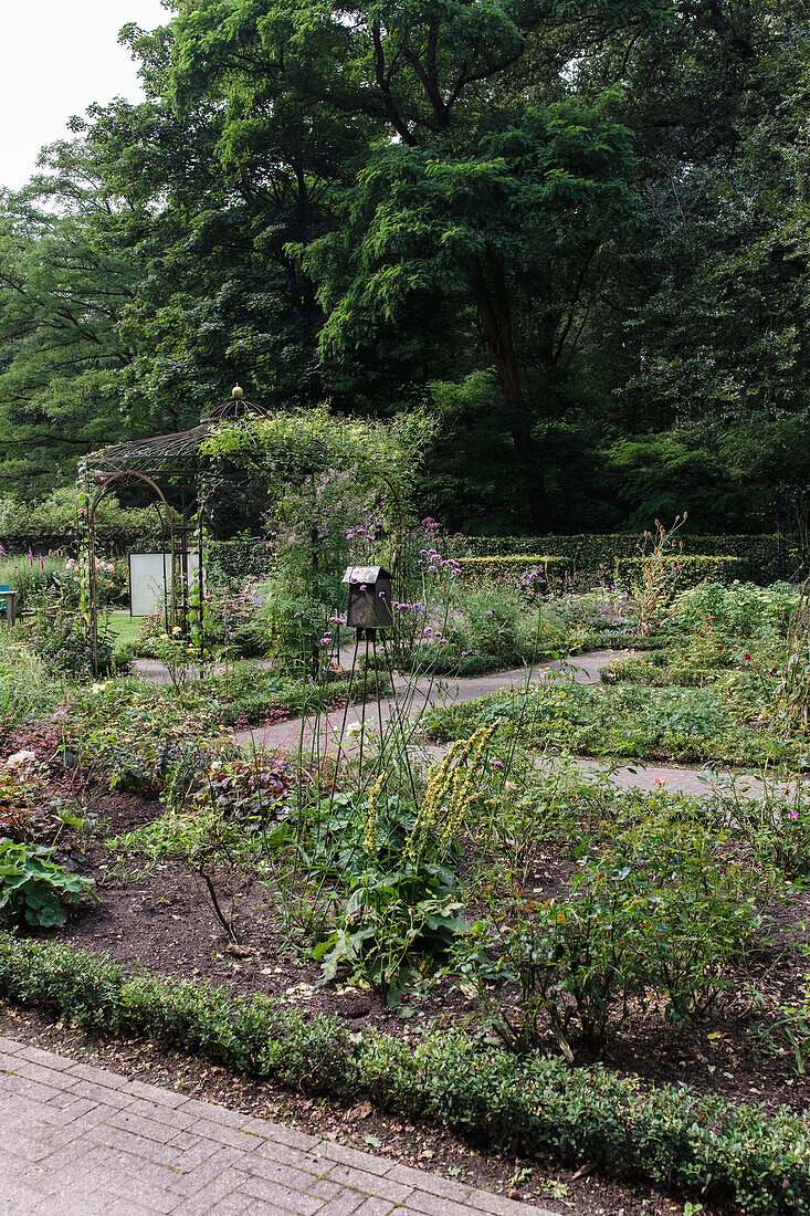 Blumenbeet mit Rankgitter und Vogelhaus im sommerlichen Garten