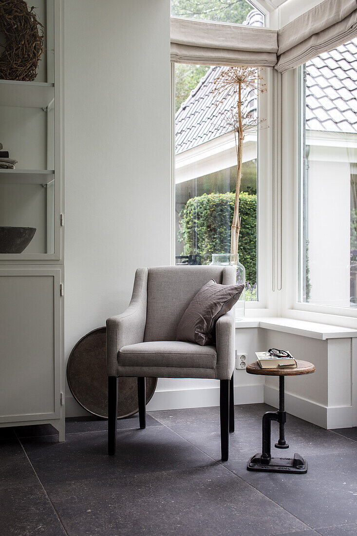 Reading corner with grey armchair and round side table by the window