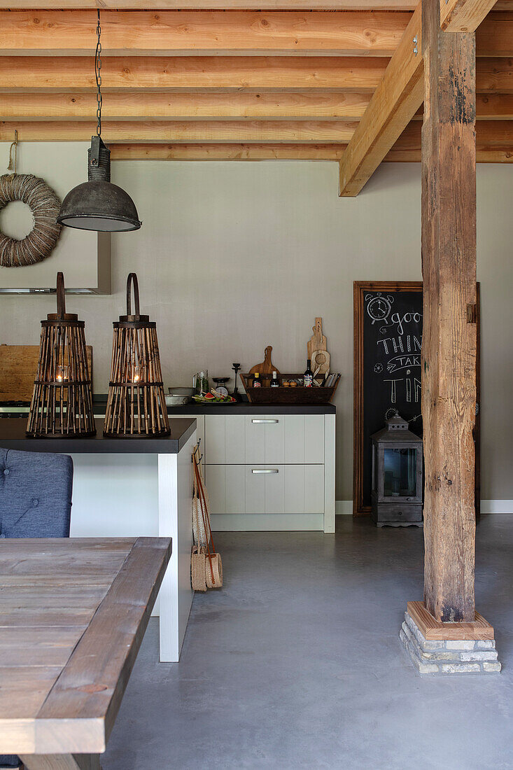 Open-plan kitchen with wooden beams, country style and hanging industrial lights