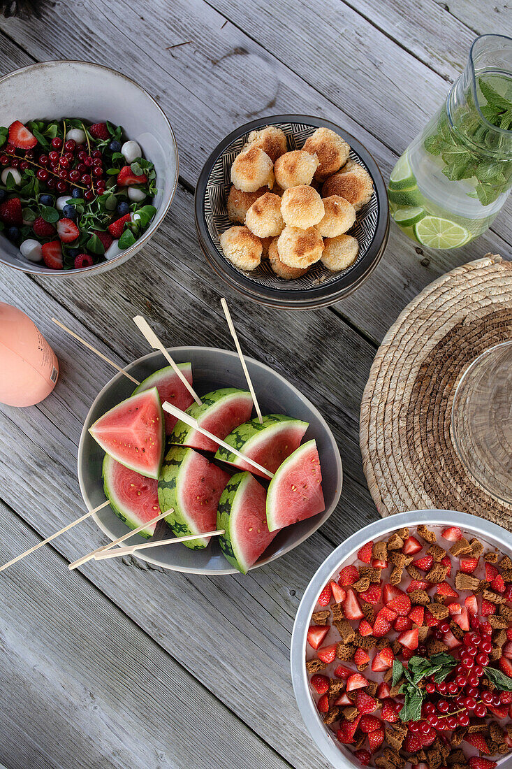 Summer picnic table with watermelon skewers, strawberry dessert and salad