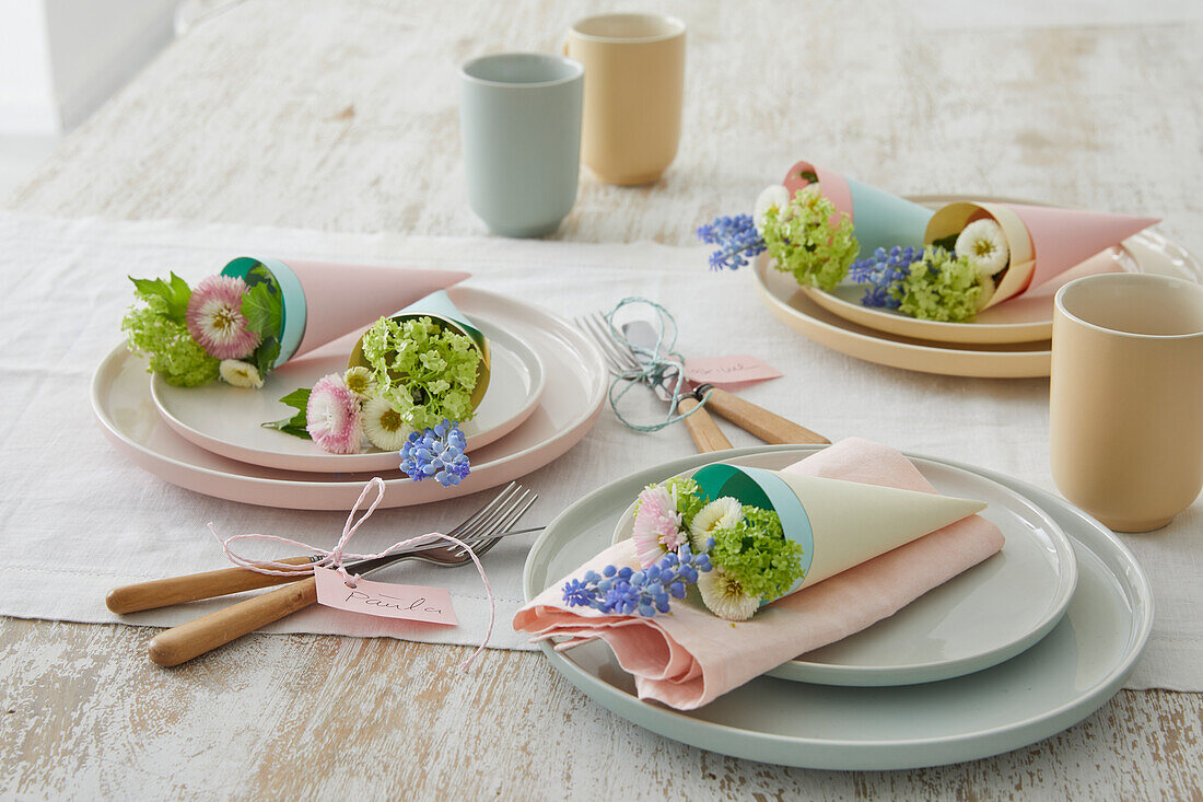 Frühlingshafte Tischdekoration mit pastellfarbenen Tellern und Blumenschmuck