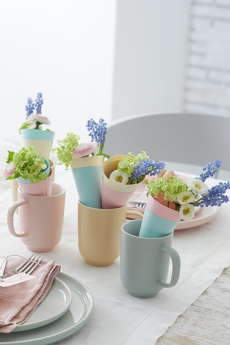 Frühlingshafte Tischdekoration mit Blumenarrangements in pastellfarbenen Tassen