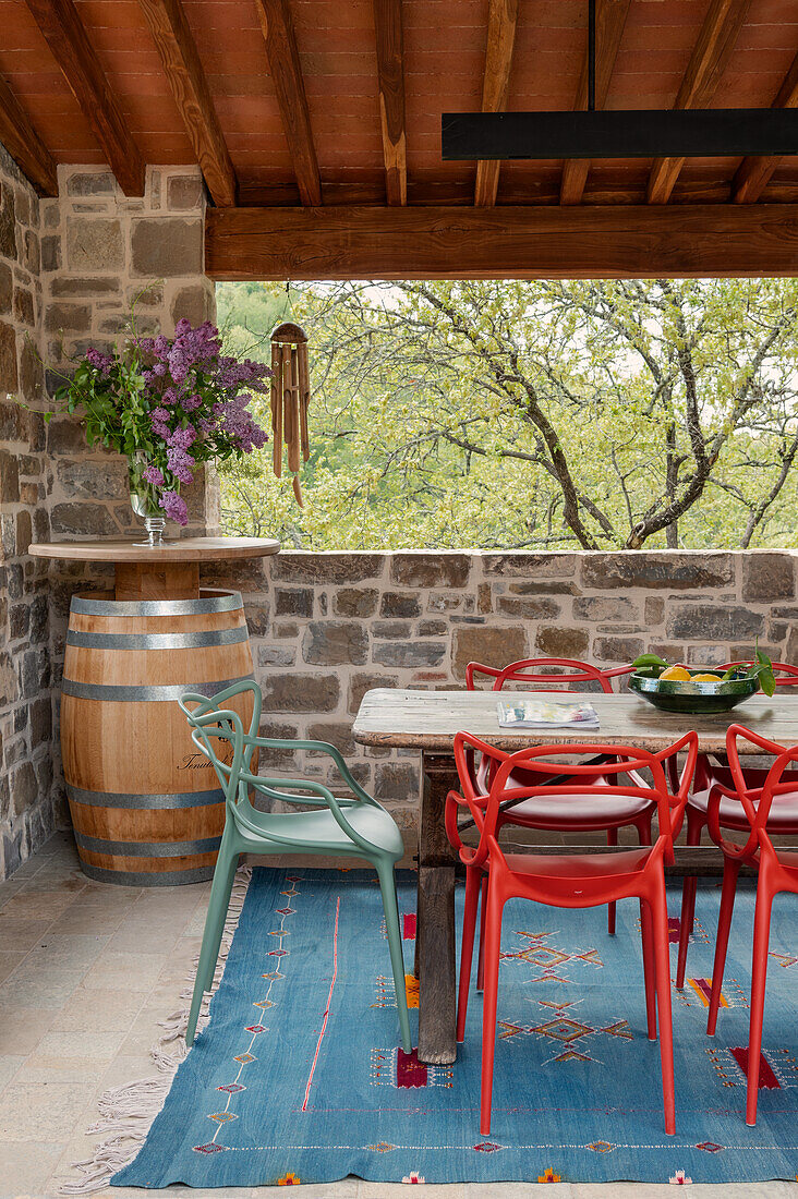 Dining area on the terrace with colorful chairs, wooden table and wine barrel