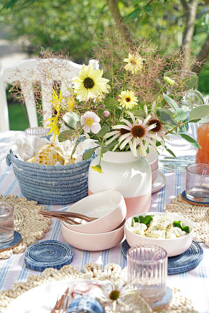 Colorful summer table setting with bouquet of wild flowers and crockery in pastel colors