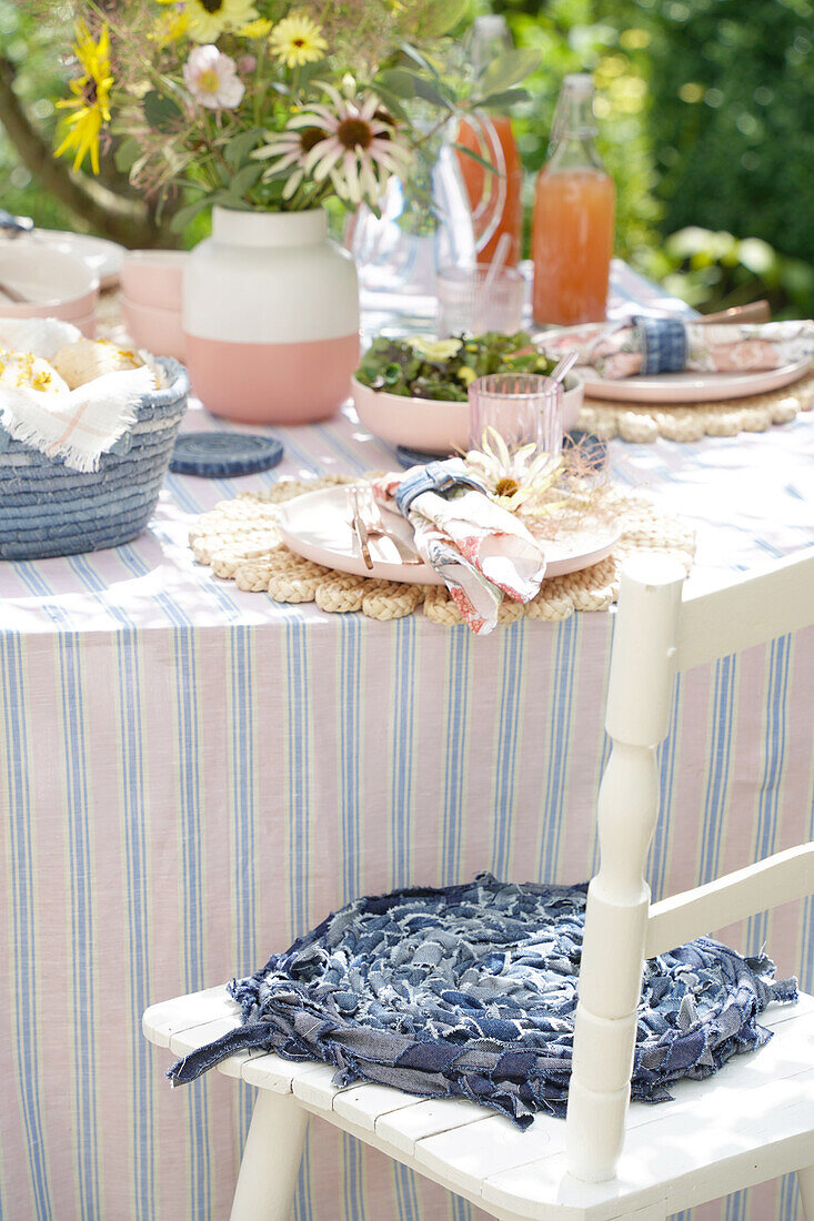 Summery table setting in the garden with bouquet of flowers and woven placemats