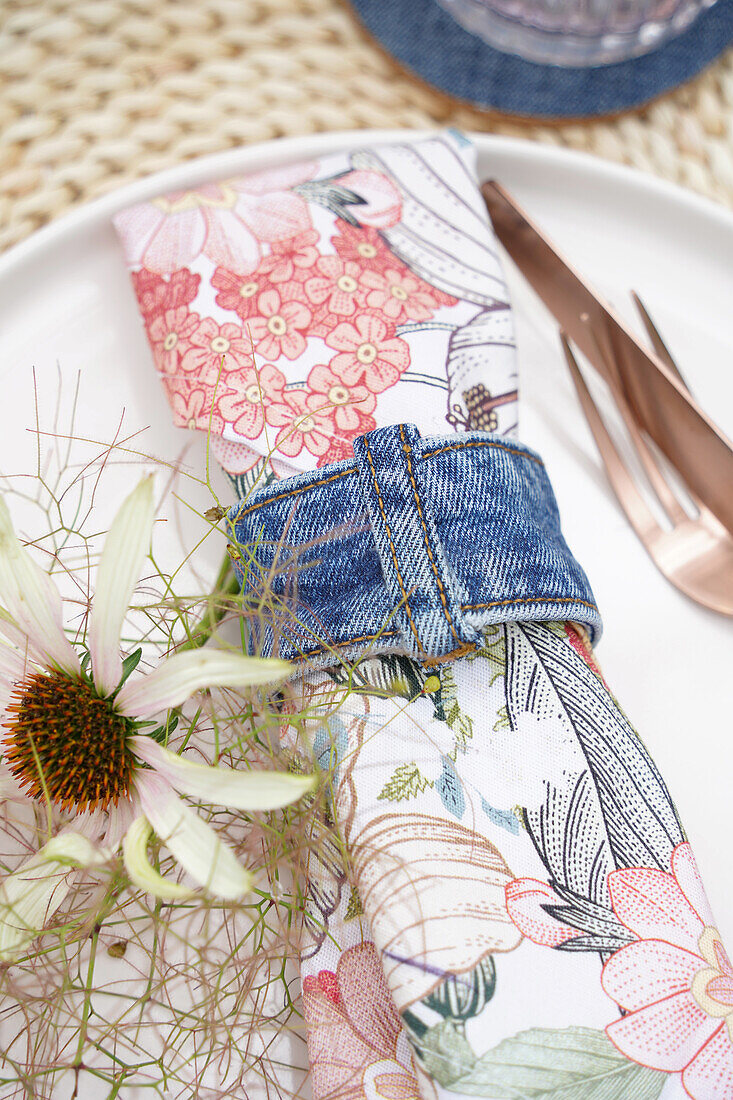 Serviette mit floralem Muster mit Jeans-Serviettenring und Blume dekoriert