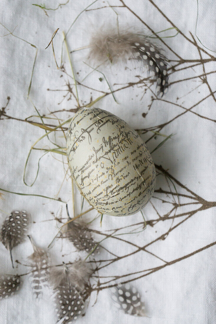 Easter egg with lettering and feather on linen cloth