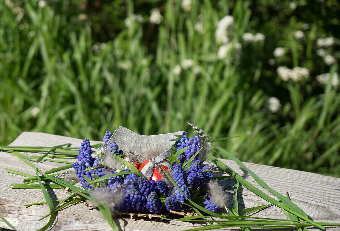 Preparation for wreath of grape hyacinths (Muscari) as an Easter nest, with Easter egg and feathers