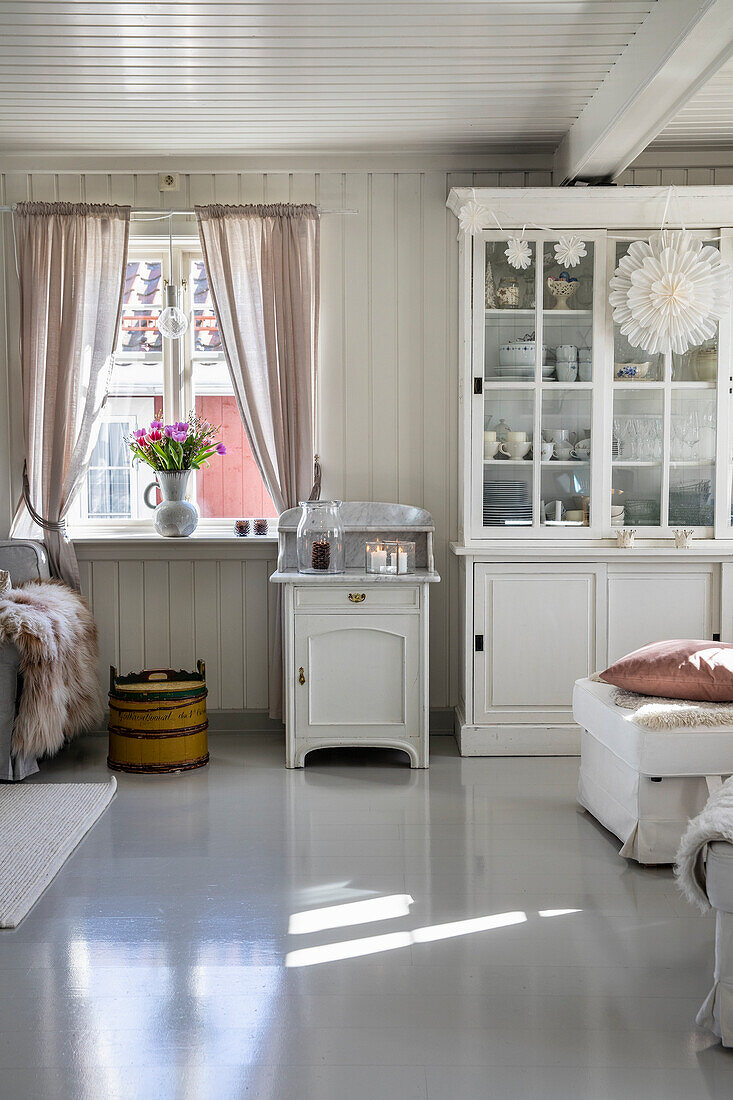 Hell eingerichtetes Wohnzimmer mit weißen Möbeln und Frühlingsblumen