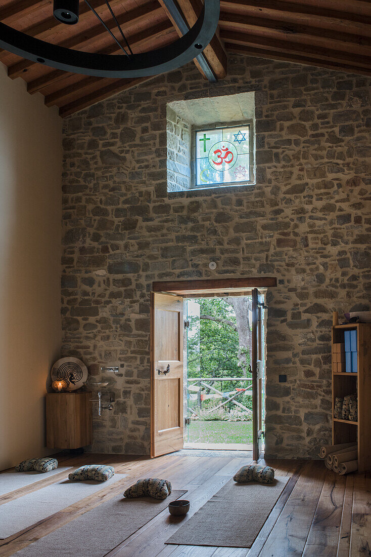 Yoga room with stone walls, wooden floor and meditation cushions