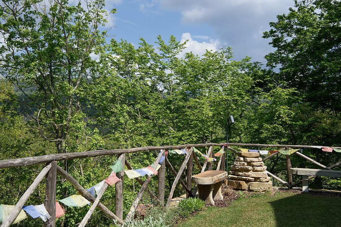 Wooden fence with colorful prayer flags and bench in a natural garden