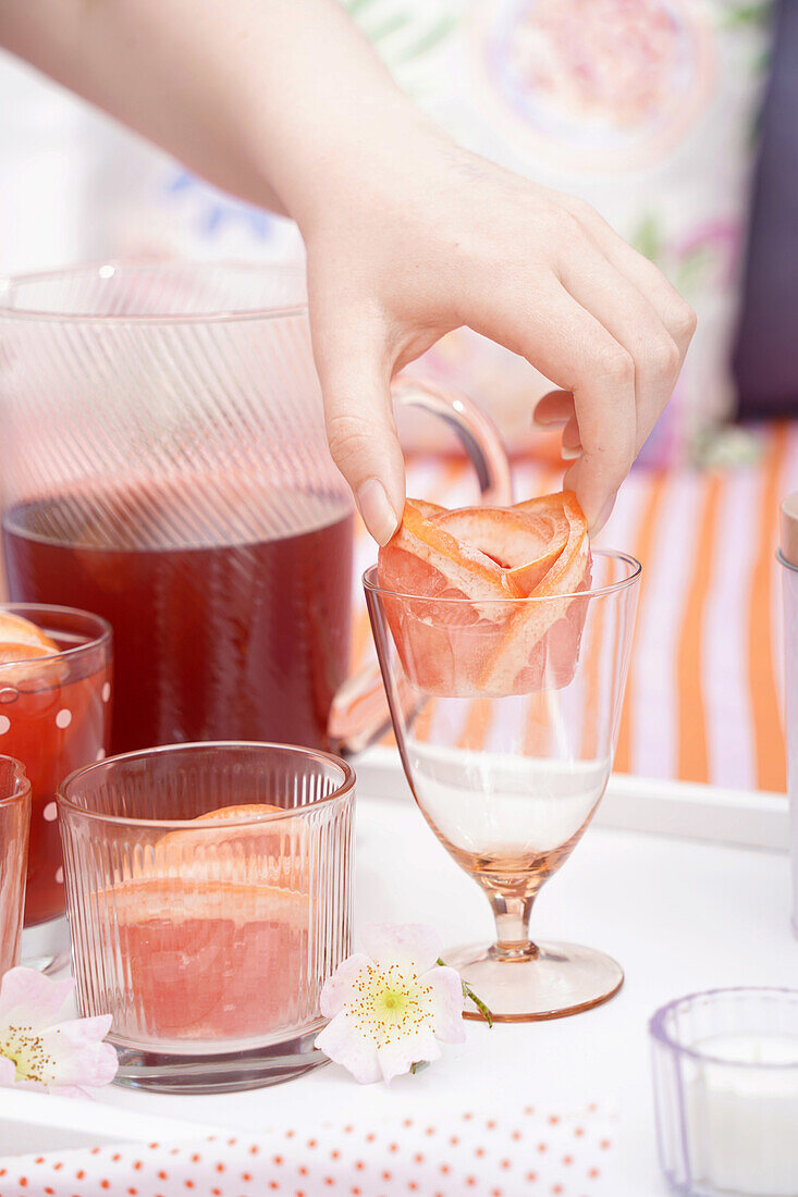 Sommerliche Getränke mit Grapefruitscheiben und Blumendeko auf weißem Tablett