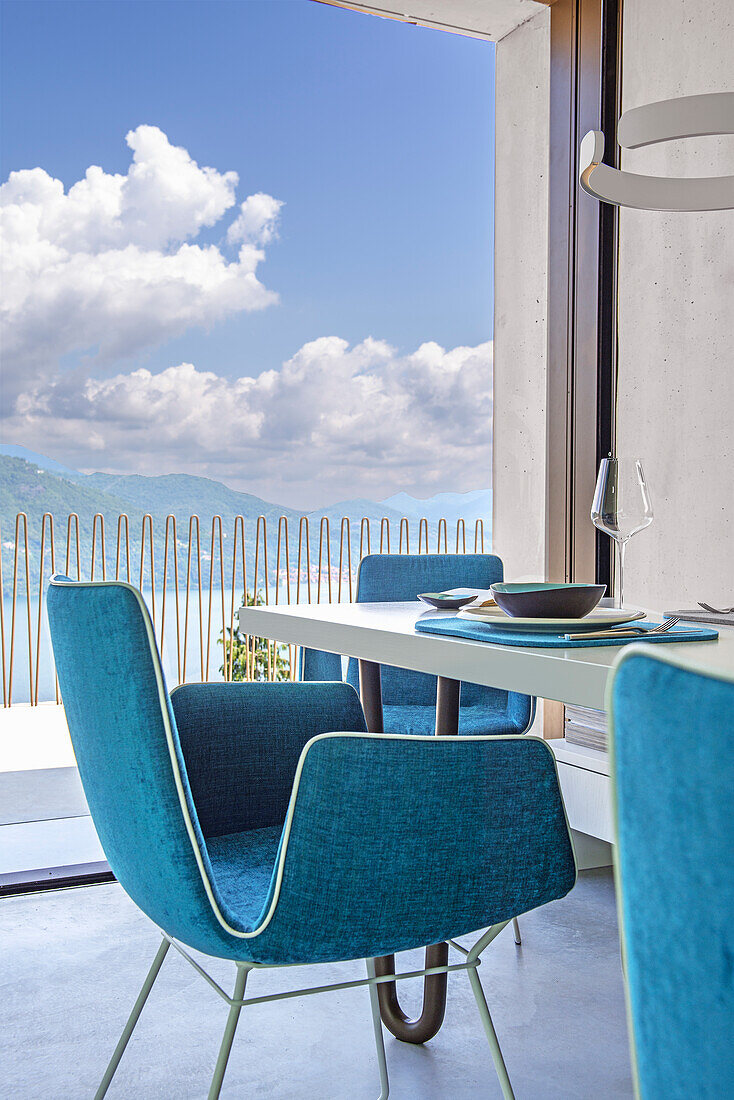 Dining area with turquoise-coloured chairs and lake view