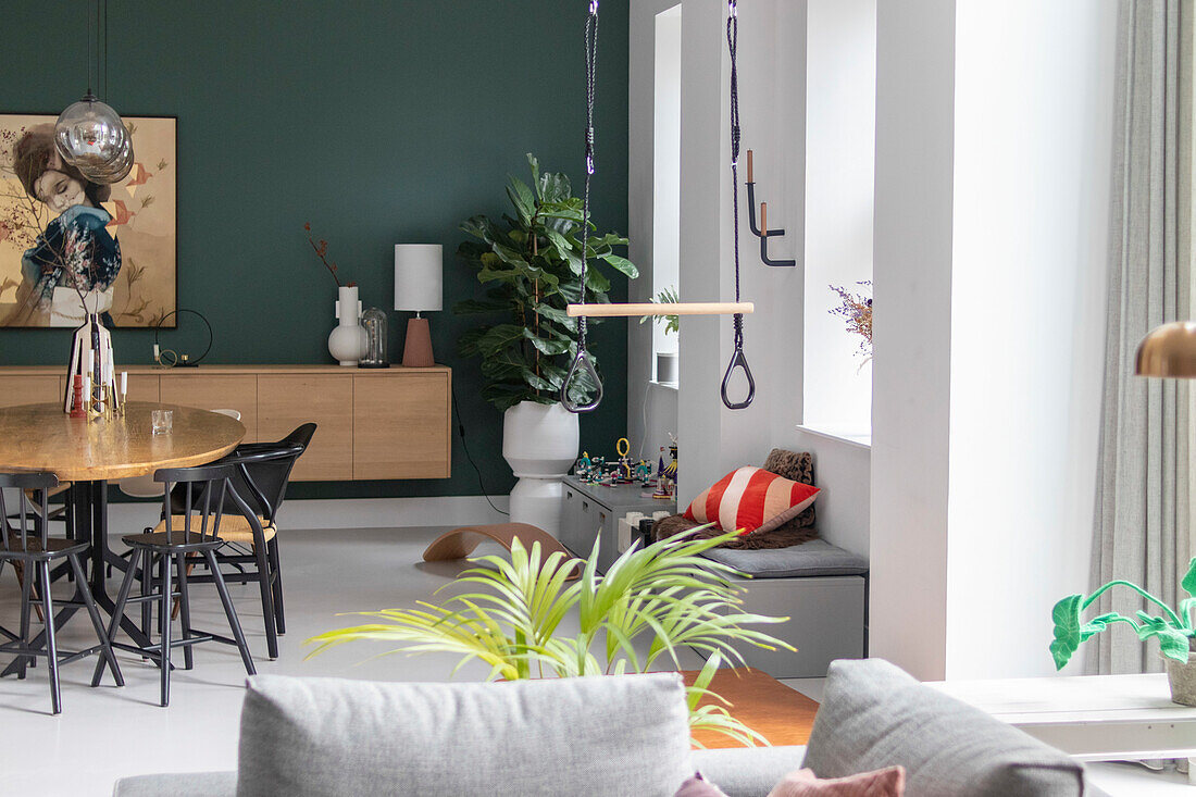 Open-plan living and dining area with dining table, bench and green plants