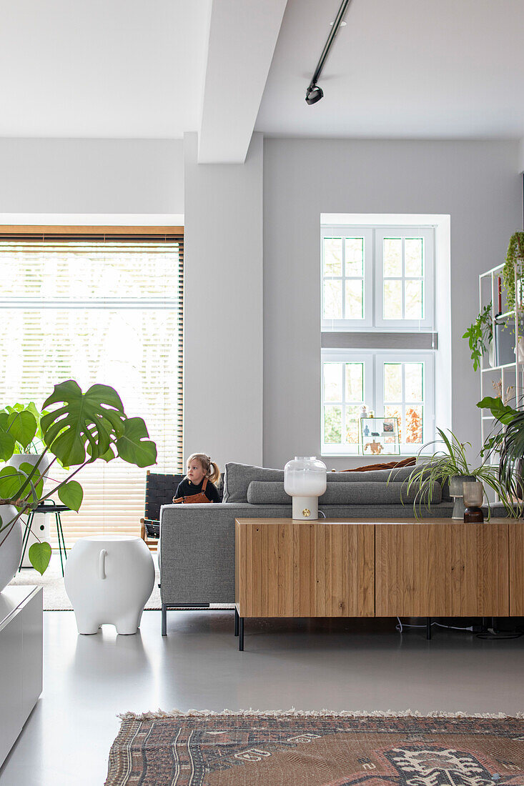 Child sits on grey sofa in living room