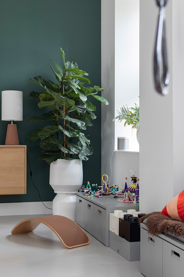 Kinderspielbereich mit Legosteinen, Feigenbaum (Ficus lyrata) und hölzernem Wobbelboard