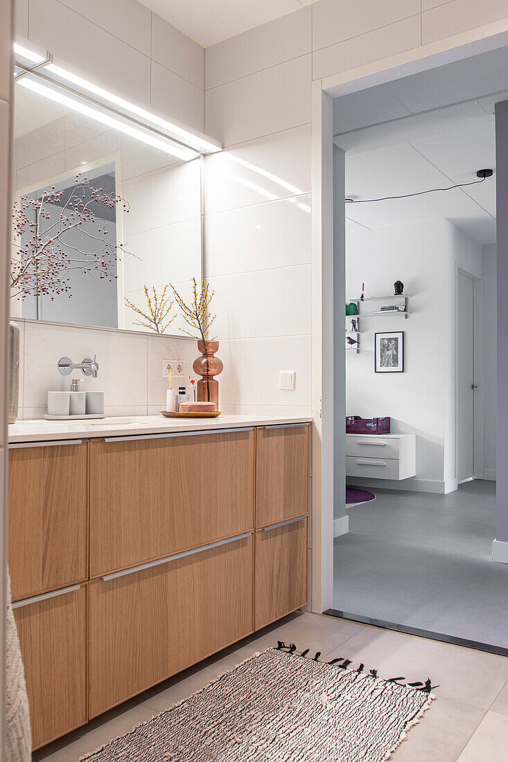 Modern bathroom with wooden vanity units and illuminated mirror