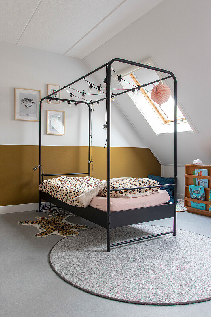 Metal four-poster bed with fairy lights, leopard bed linen in the children's room