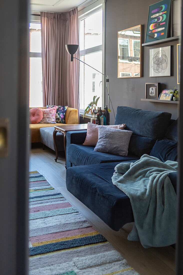 Living room with blue sofa, striped carpet and pink curtains