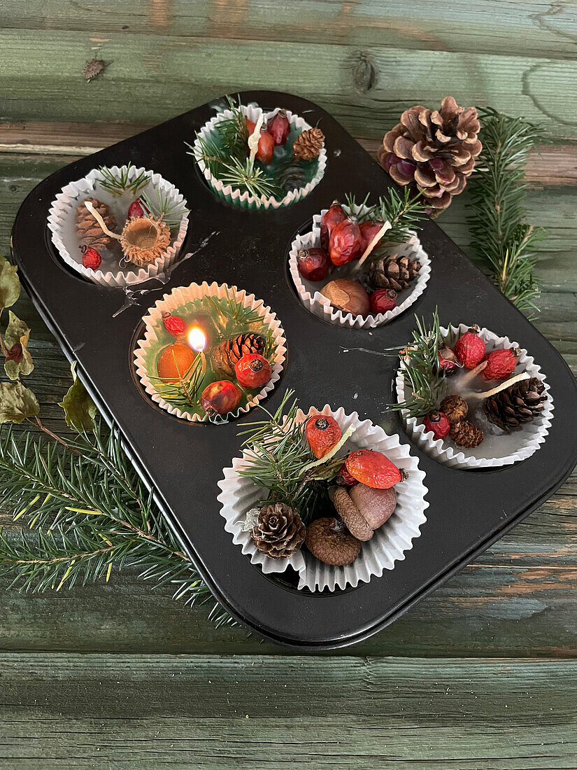 DIY forest candles with fir twigs, rosehips and cones in muffin molds