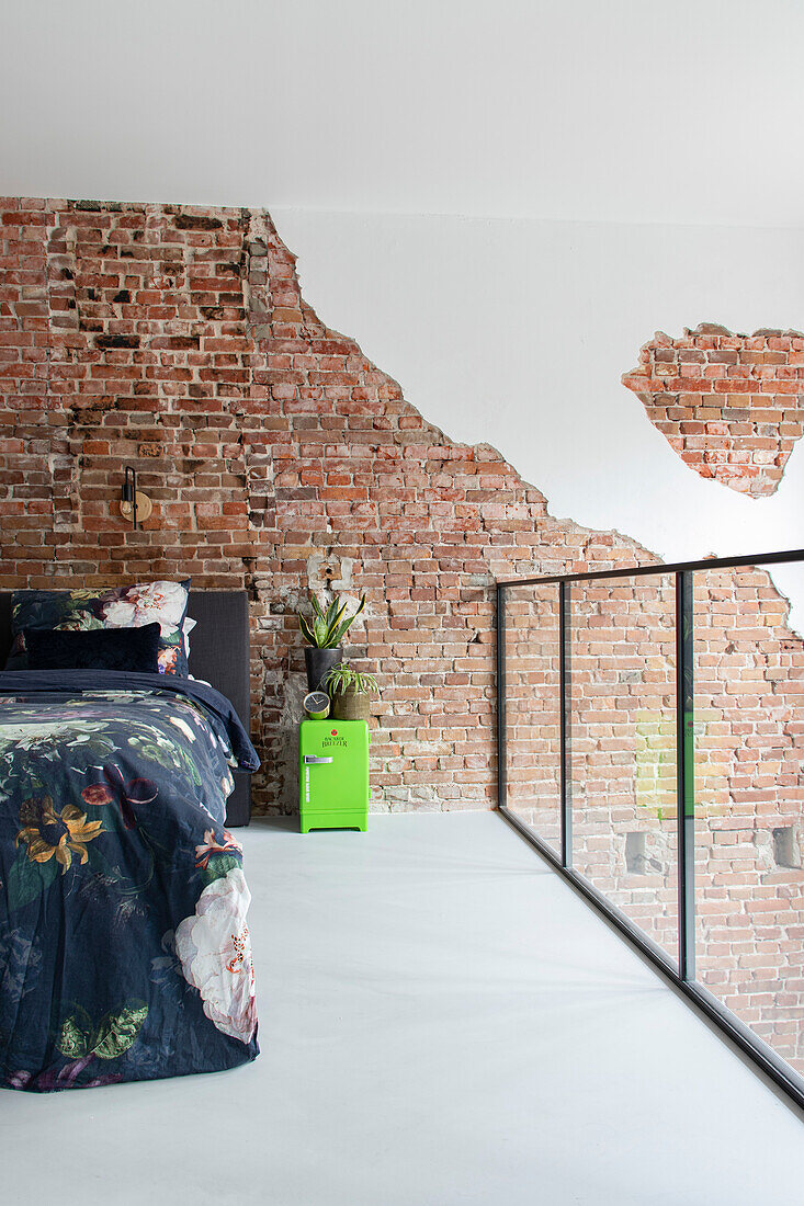 Bedroom with floral bed linen and exposed brick wall